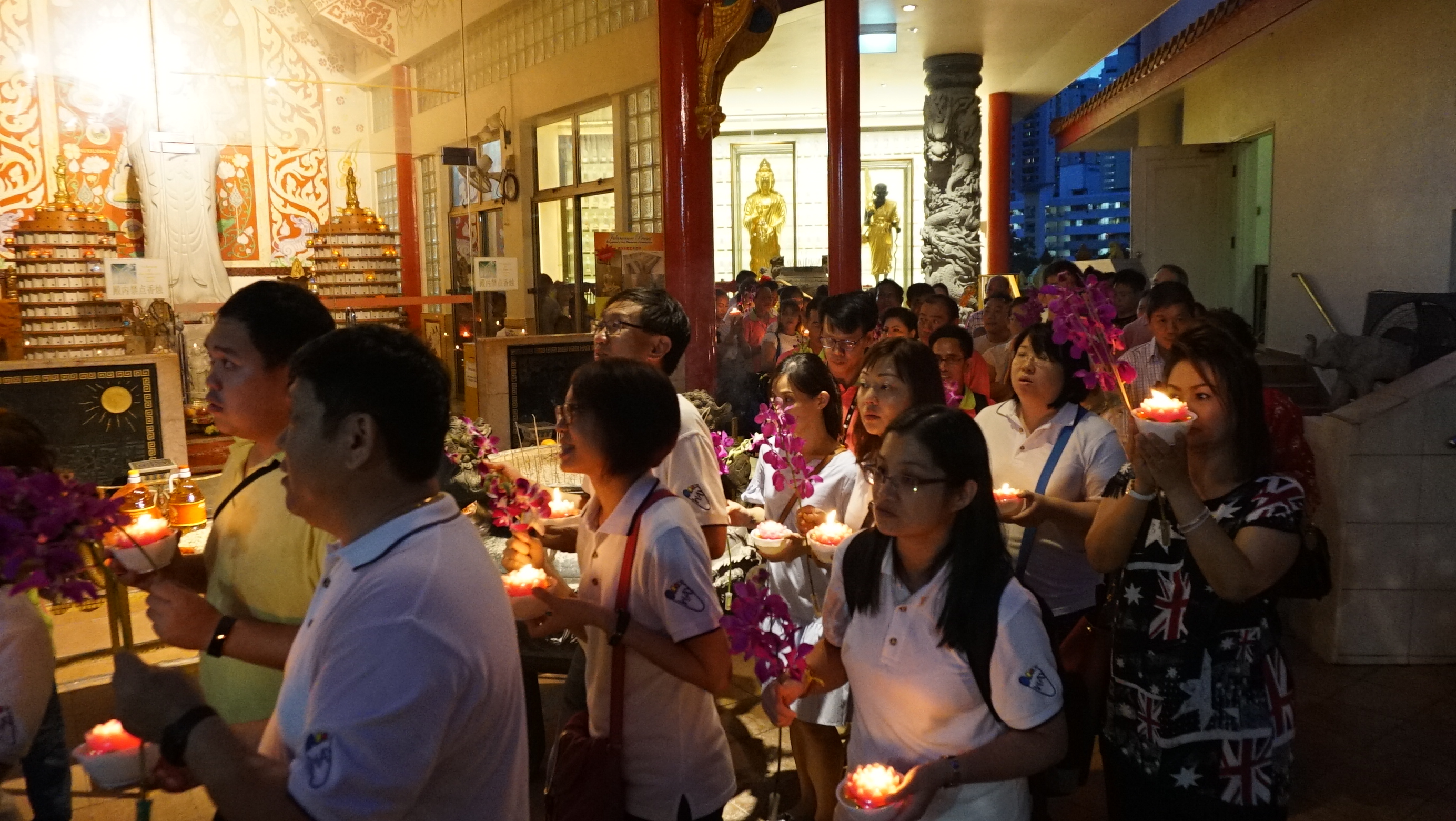 Devotees walking around the temple grounds with candles as part of Vesak Day rituals.