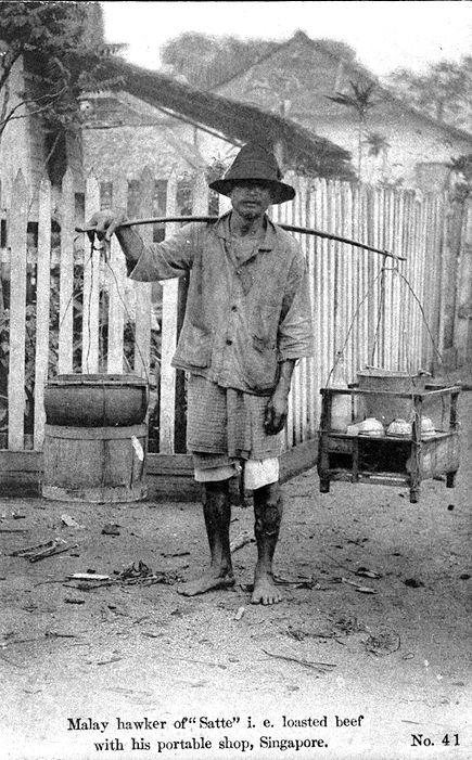 Malay hawker with his portable shop selling satay.