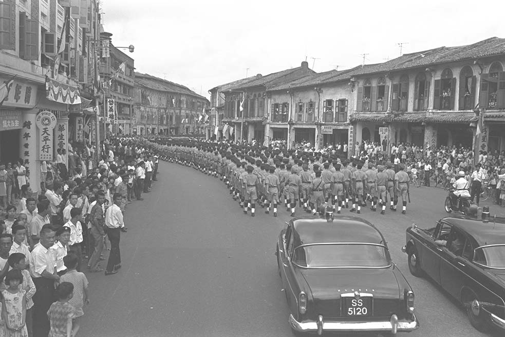 A contingent from Singapore Police Force marching down Tanjong Pagar Road on the day of the first-ever National Day Parade in 1966, watched by spectators lining both sides of the road and from the residences. (c1966. Image from Ministry of Information and the Arts Collection, courtesy of National Archives of Singapore)