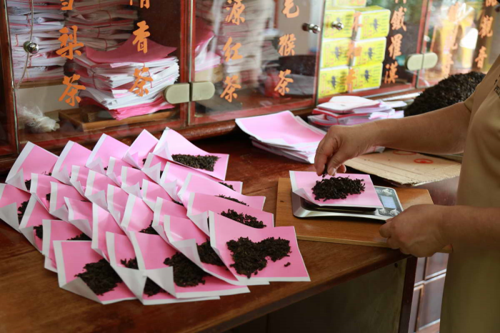 (Left) Pek Sin Choon’s packing of tea leaves in pink paper used for Chinese medicine – a tradition continued from the past.