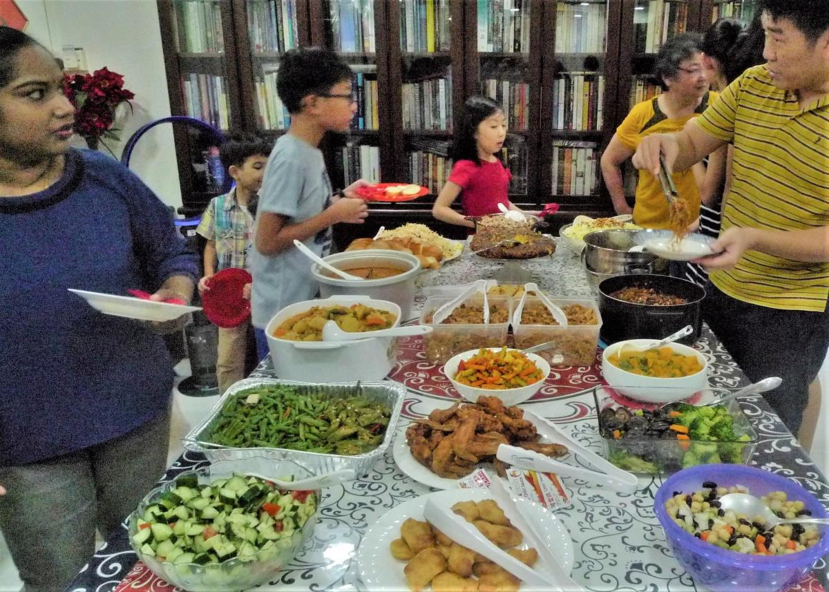 Members socialise and enjoy a potluck dinner at a Nineteen Day Feast meeting. Image courtesy of National Heritage Board.