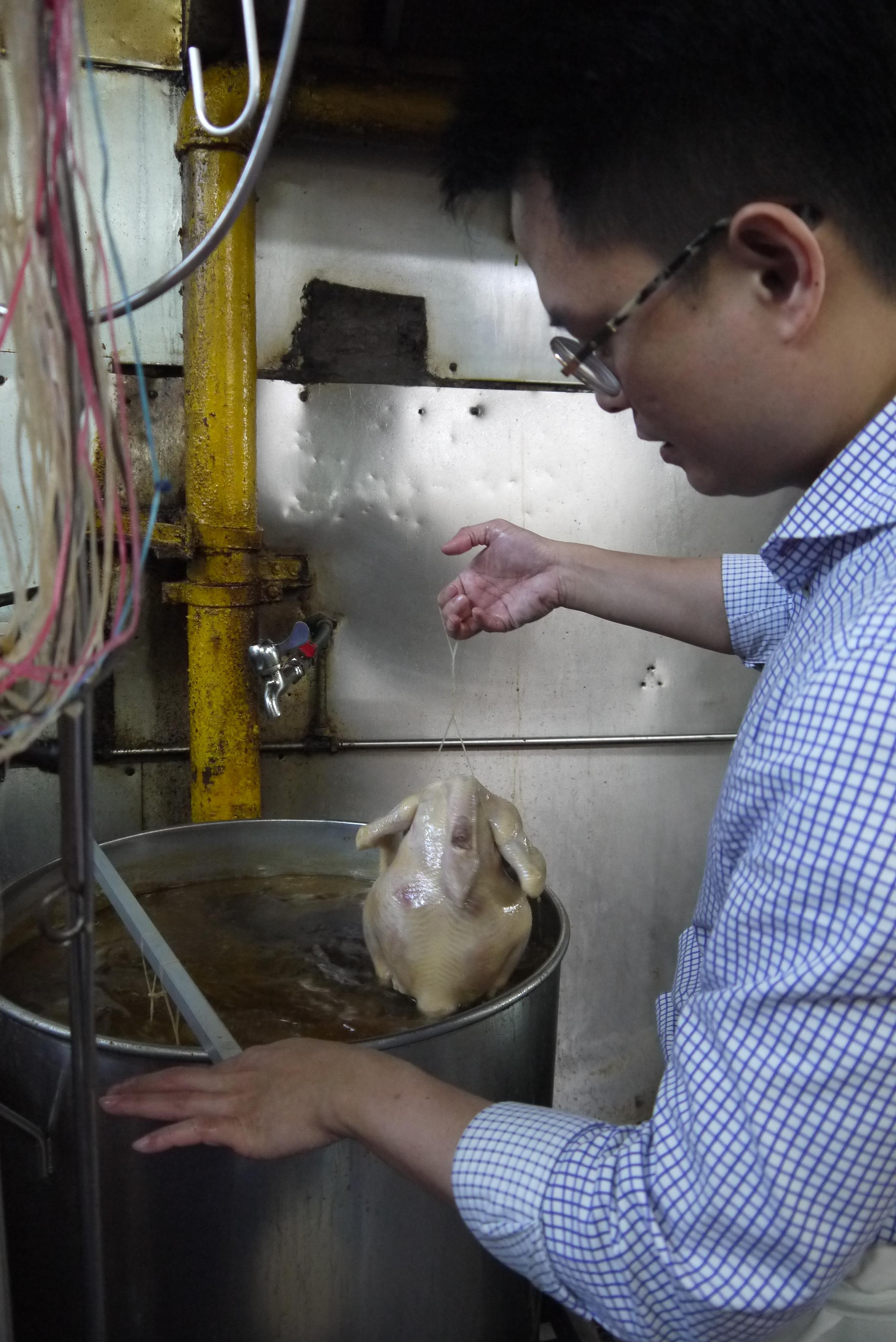 Mr Benjamin Boh of Golden Mile Thien Kee Steamboat Restaurant dipping chicken in and out of boiling chicken stock, before letting it cook in the broth.