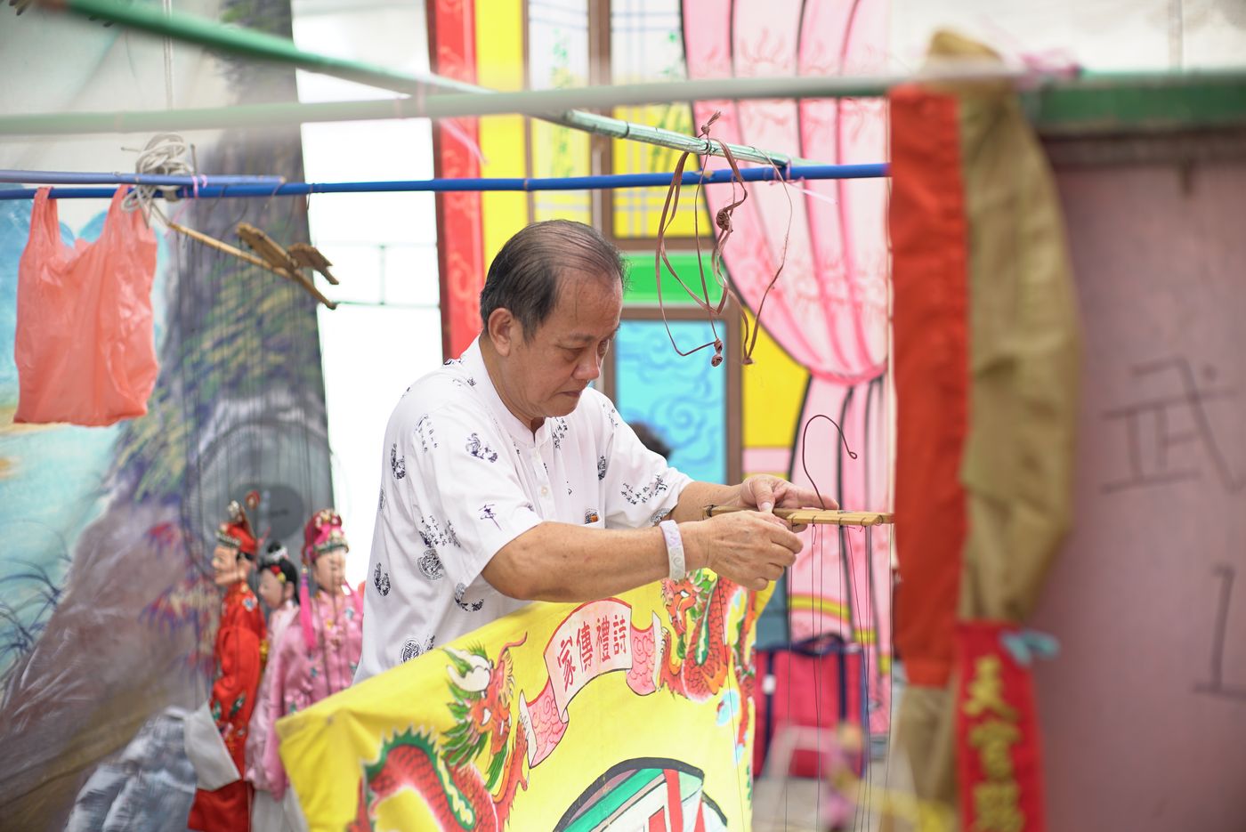 A practitioner maneuvering backstage for a Hokkien string puppet performance
