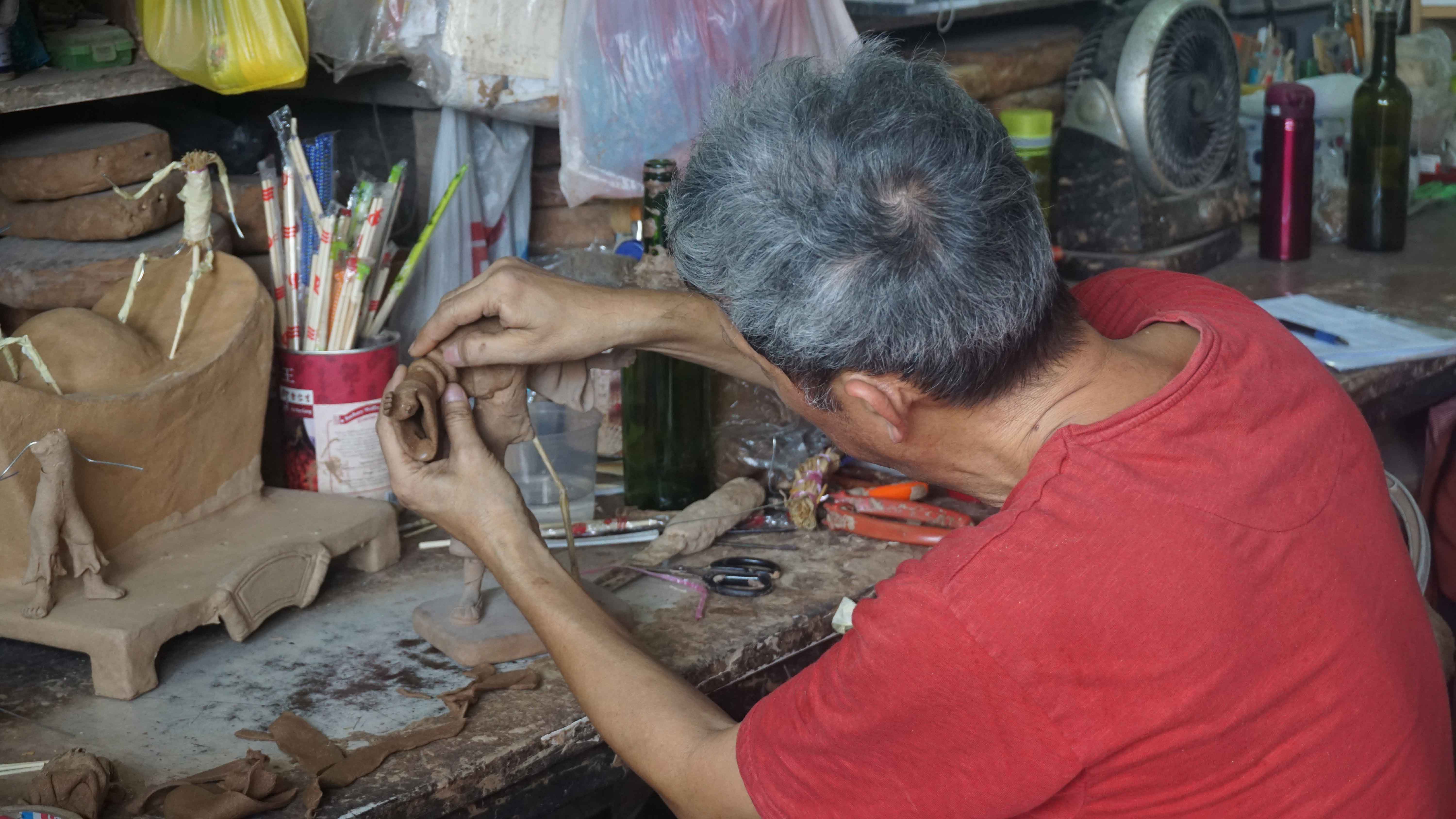 Mr Amos Tay moulding a figurine using joss stick dough