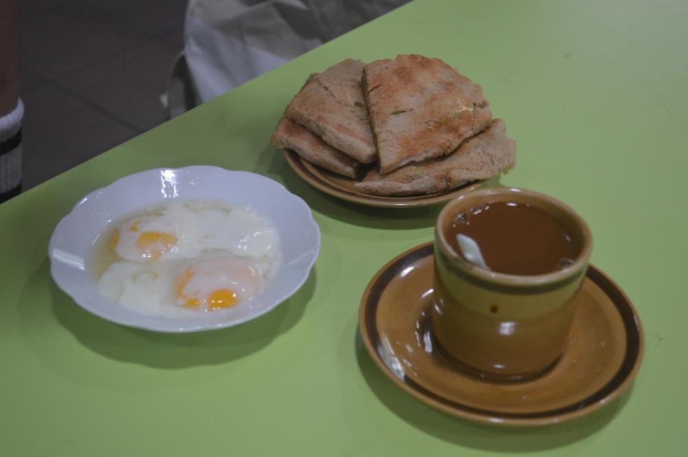 A typical traditional style of breakfast, often referred to as “Nanyang” breakfast, comprising soft-boiled eggs (left), kaya toast (top), and a cup of coffee or tea.