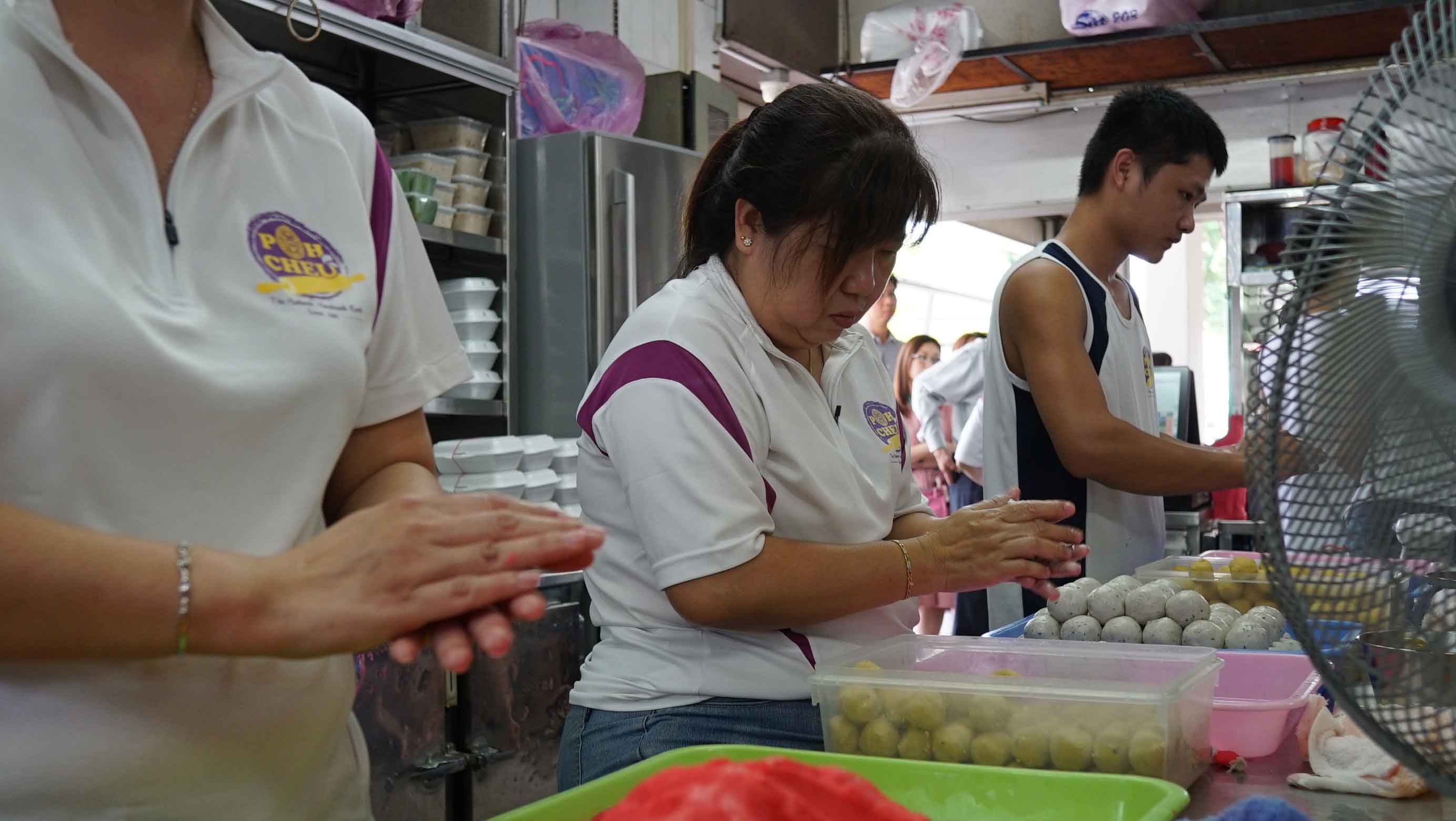 Kitchen staff rolling multi-coloured dough into balls