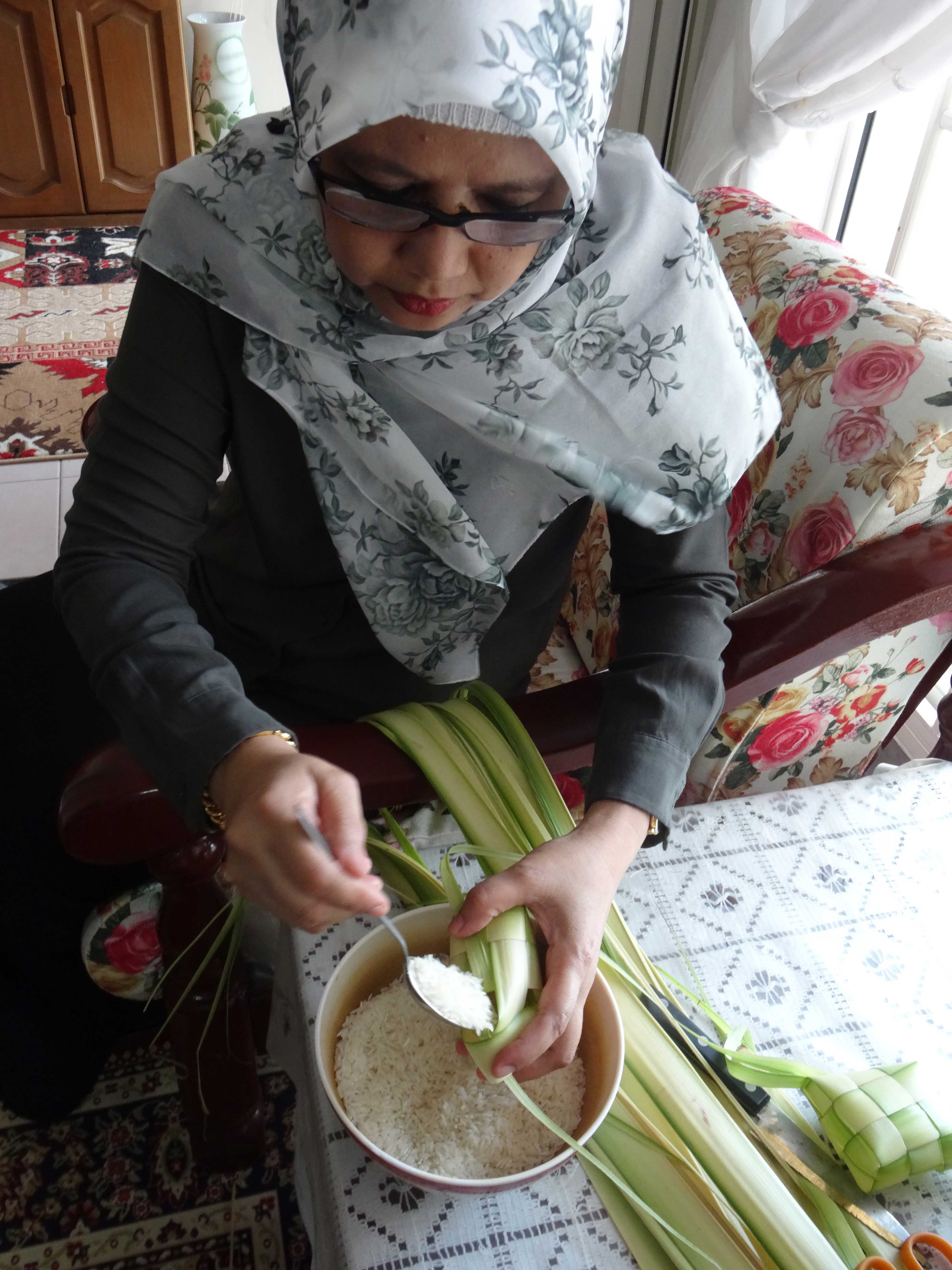 Madam Sabrah’s daughter, Madam Anita bte Tompang, filling the <i>ketupat</i> pouch with rice