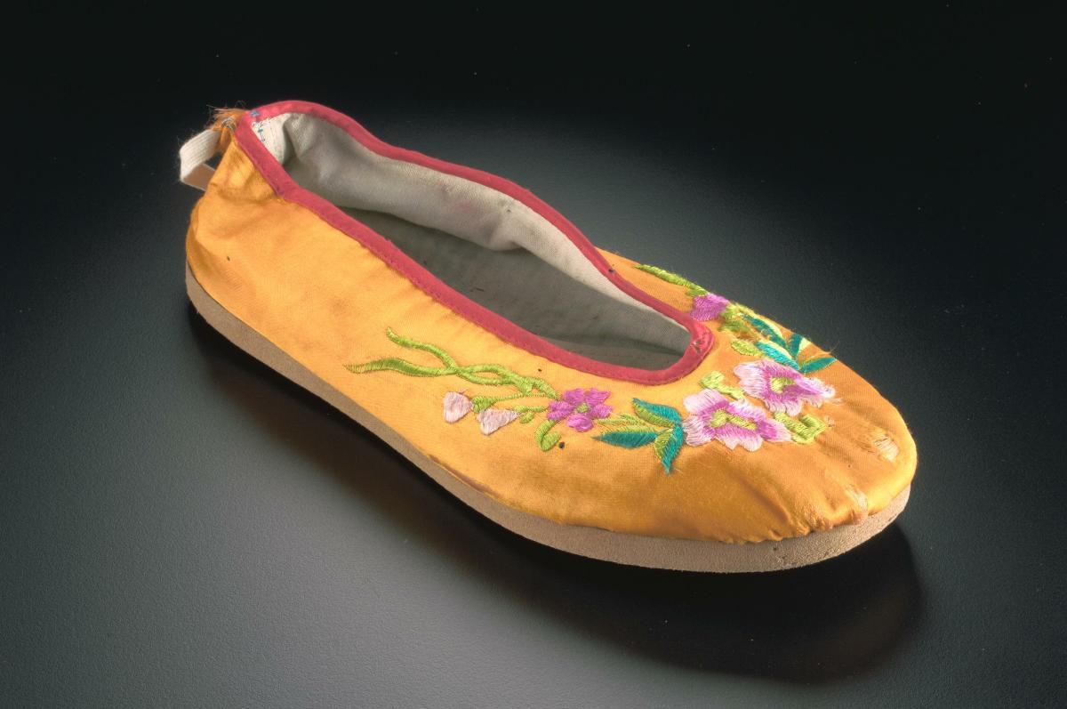 An orange shoe with embroidered floral motifs worn in a Chinese opera ...
