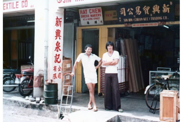 黄坤腾的儿子昭宝（左）站在乞来街的原店前留影。