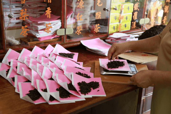(Left) Pek Sin Choon’s packing of tea leaves in pink paper used for Chinese medicine – a tradition continued from the past.