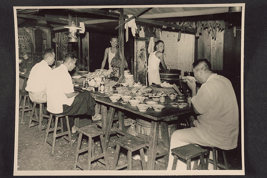 <strong>Diners gathered around a communal table at a hawker stall<br>
</strong>
c1950<br>
XXXX-15583