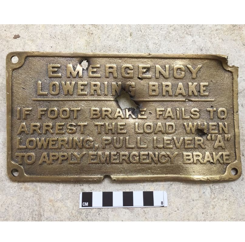 <em>A lifeboat emergency brake instruction plate, pierced by shrapnel from the bombing on 5th February, 1942.
<p></p></em>
