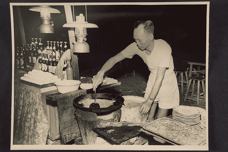 <strong>Photograph of hawker cooking by the light of kerosene pressure lamps<br>
</strong>c1950<br>
XXXX-15575