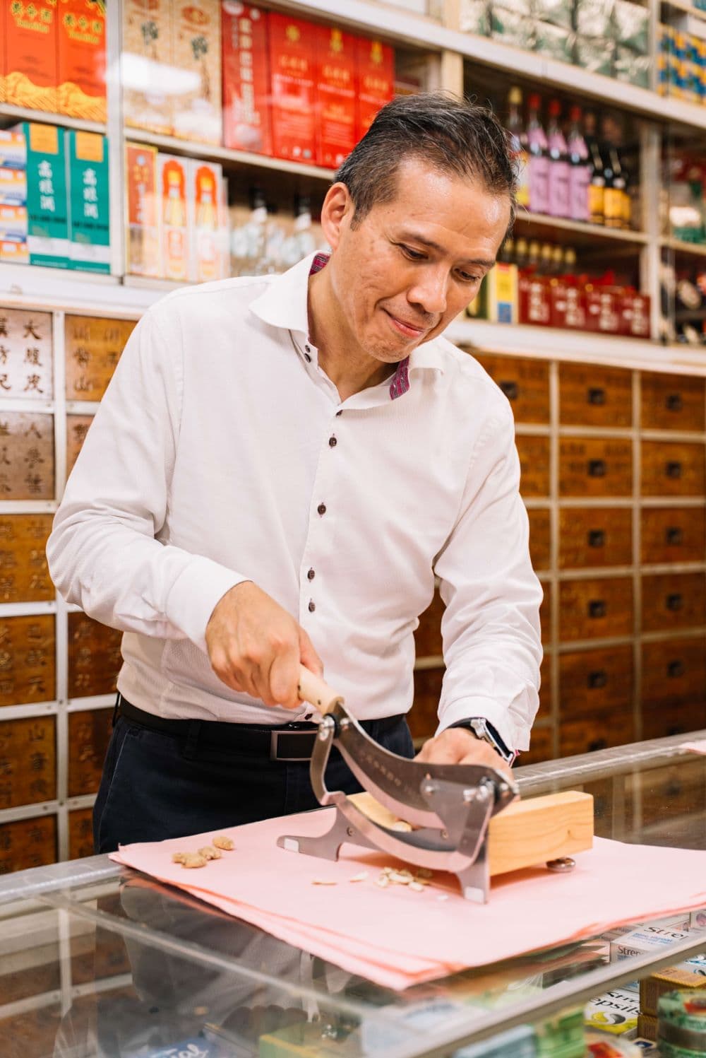 Chin Siong preparing medicinal herbs, slicing off the roots, for use in traditional Chinese remedies.