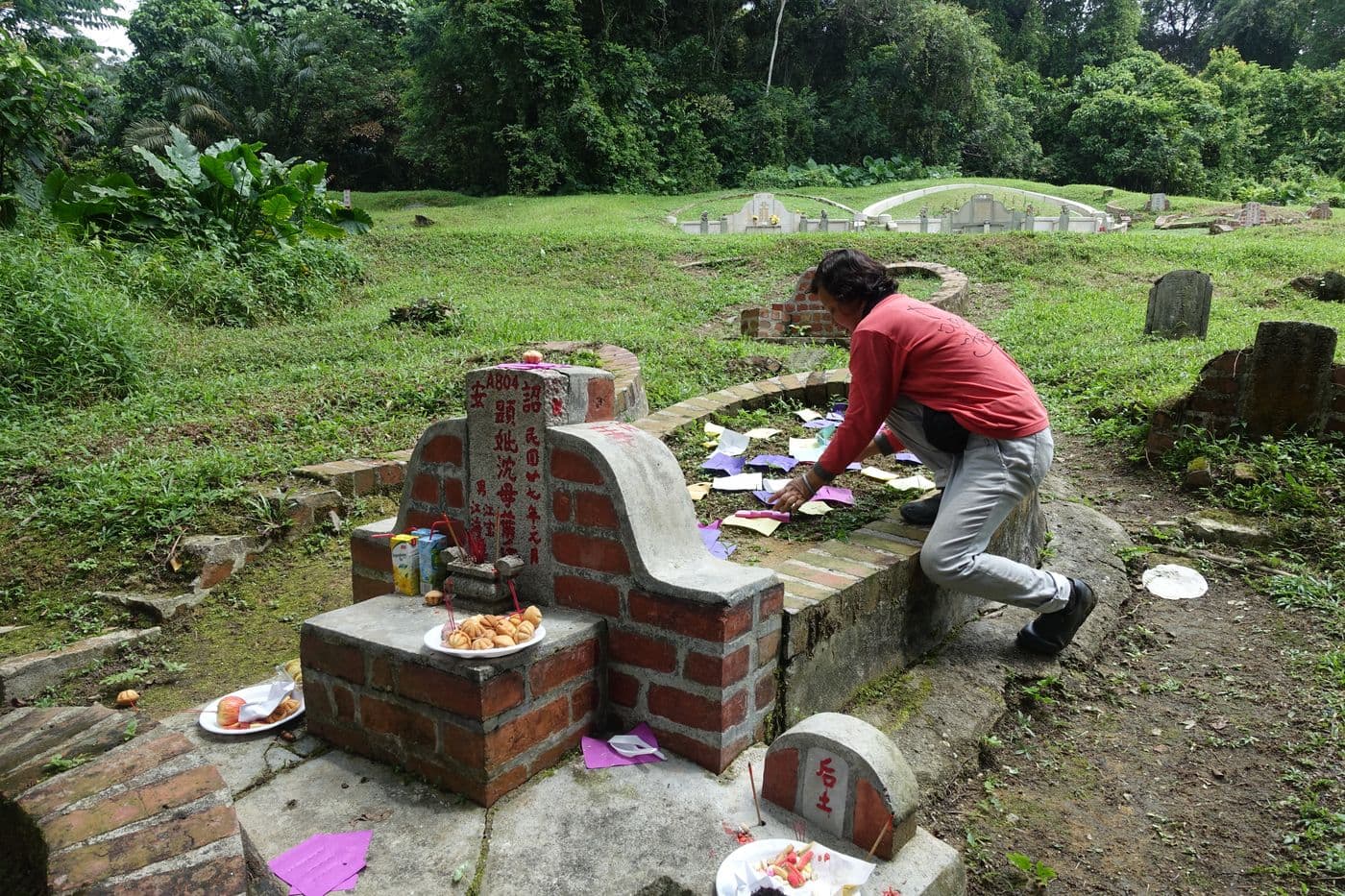 Tomb keeper Madam Queenie Quek tending to a grave in Bukit Brown Cemetery.
