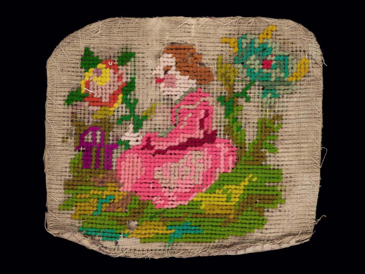 Needlework sampler with motif of a girl seated between two flowers