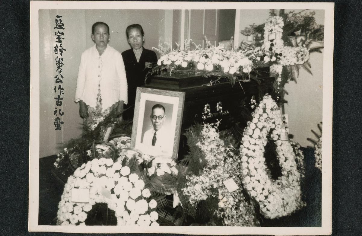 Two 'bibiks' standing next to a coffin
