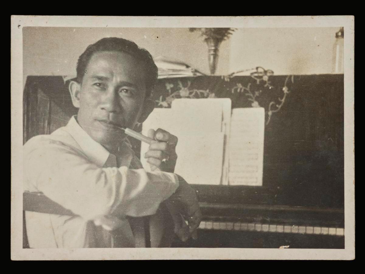 Photograph of Zubir Said posing at his piano in his home at 190A Joo Chiat Place