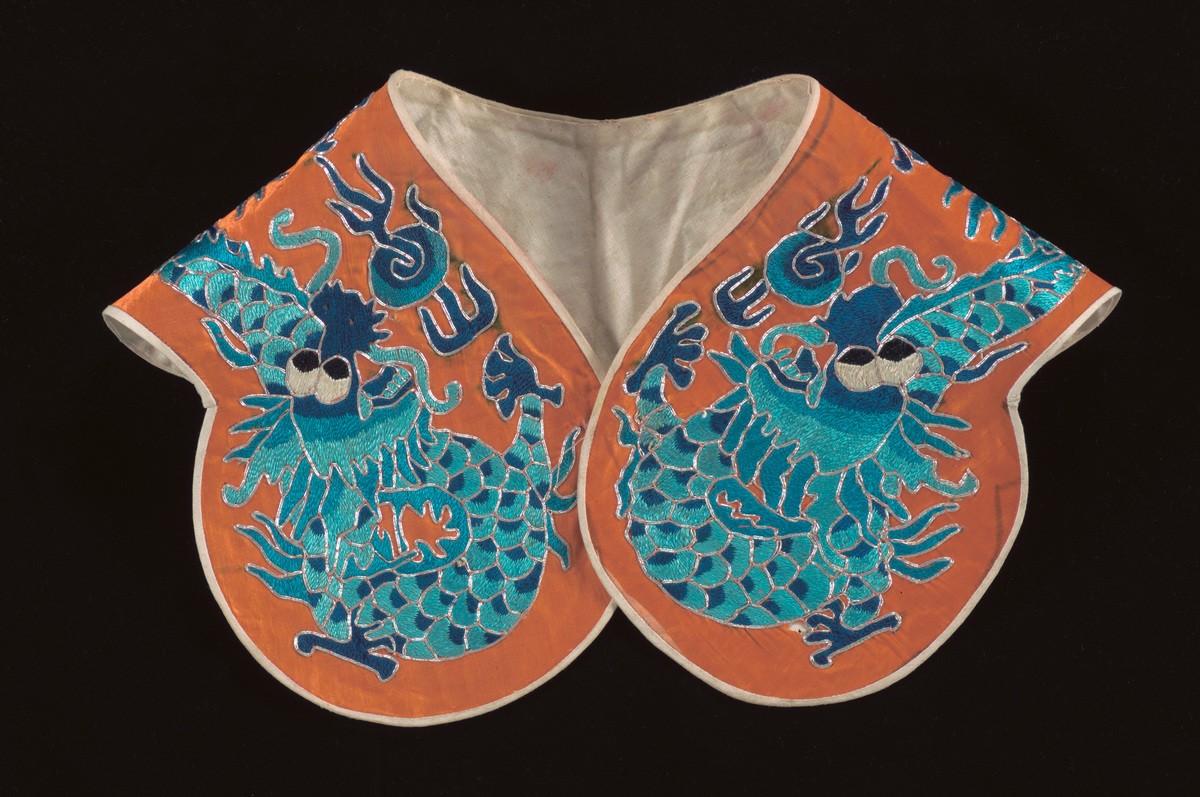 An orange shoulder piece embroidered with blue dragon motifs worn by a ‘wu sheng’ in a Chinese opera
