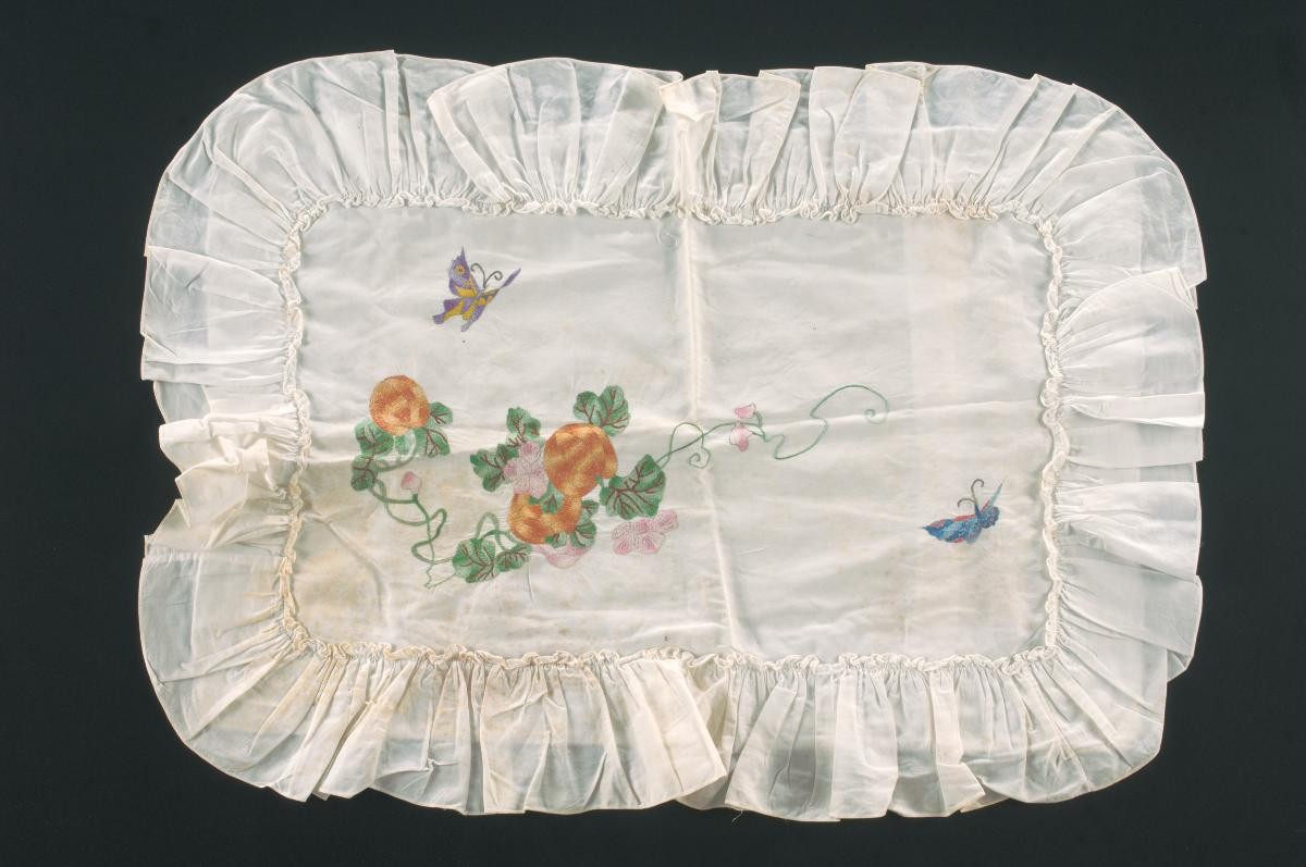 White pillowcase with an embroidered butterfly and floral motif
