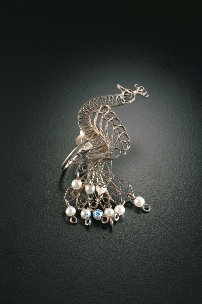 A pair of peacock-shaped ear rings with pearls that belonged to a notable women's rights activist