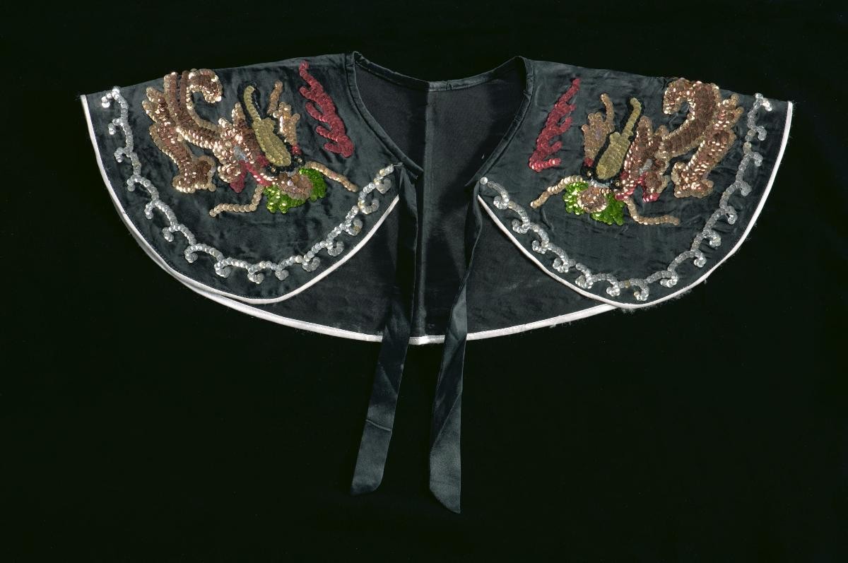 A black shoulder piece with sequined dragon motifs worn by a court official in a Chinese opera