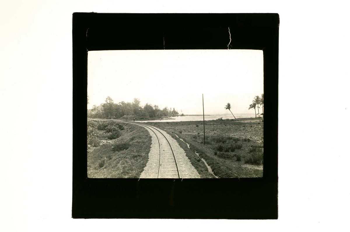 A glass lantern slide depicting a railway track cutting through a coastal area