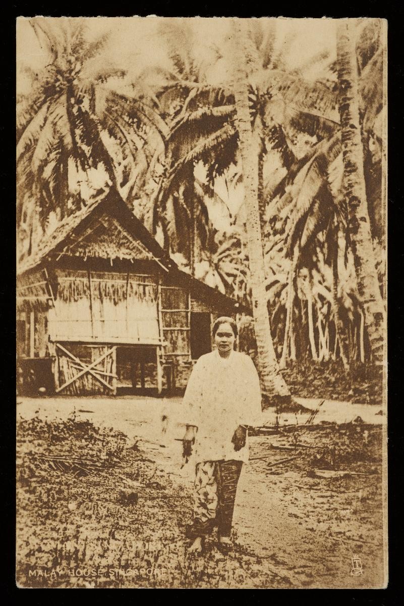 Malay lady standing in front of a kampong