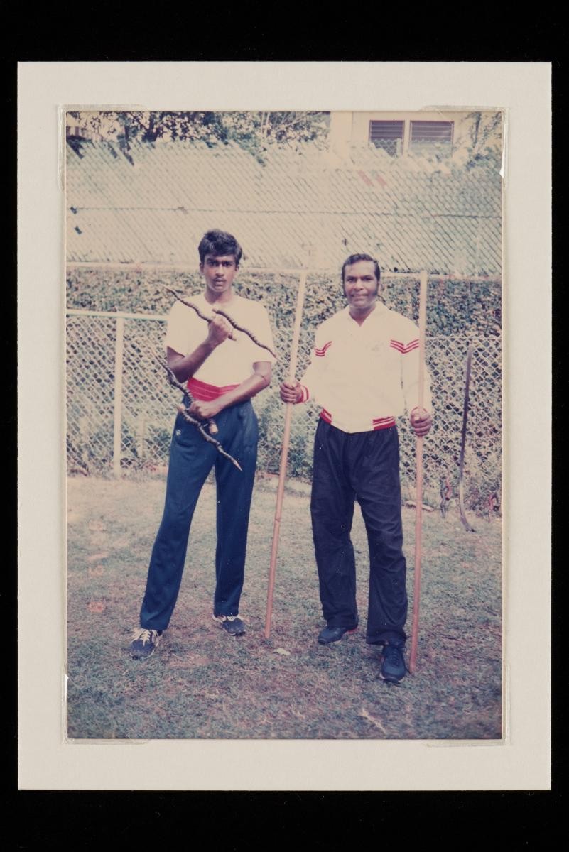 Photograph of Edward with son Edward Jeevan Jr posing with Madu & Silambam stick