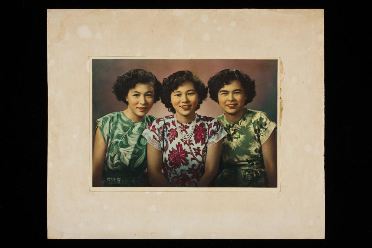 Hand-coloured studio portrait of three Chinese women in matching cheongsams