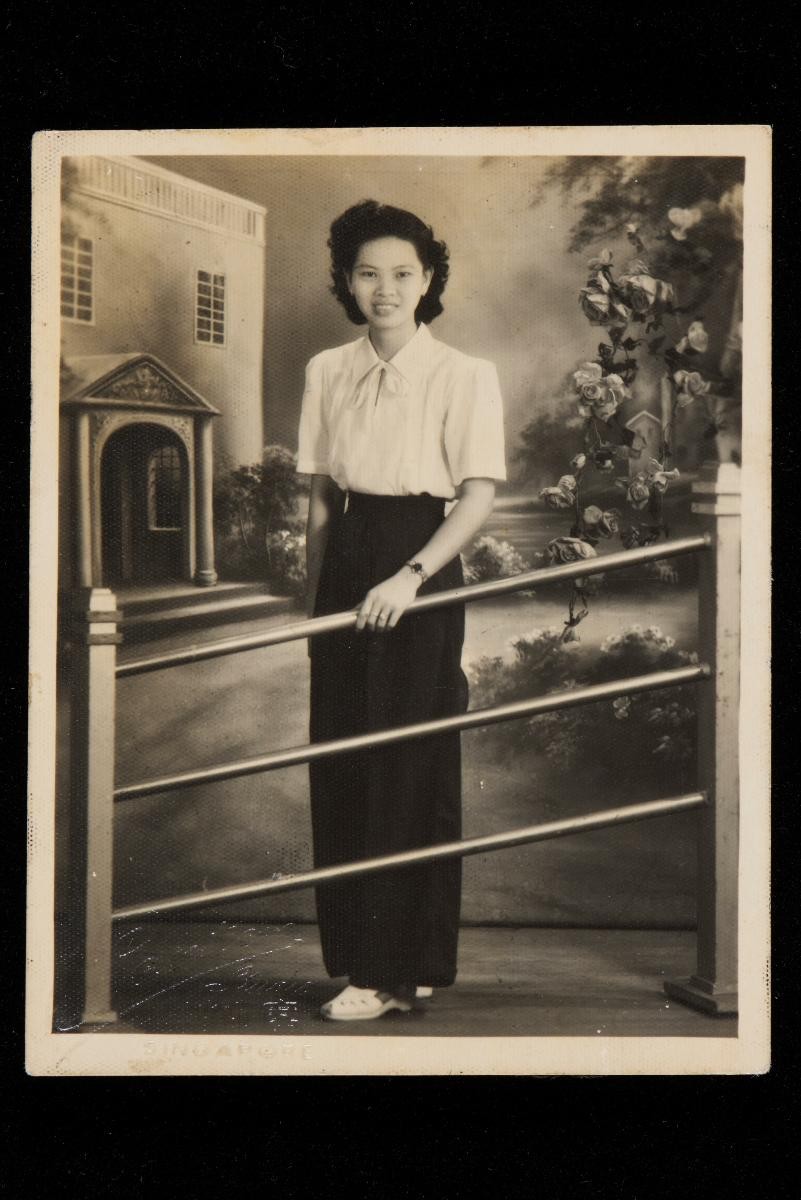Studio portrait of a young Chinese woman with backdrop of a house and garden