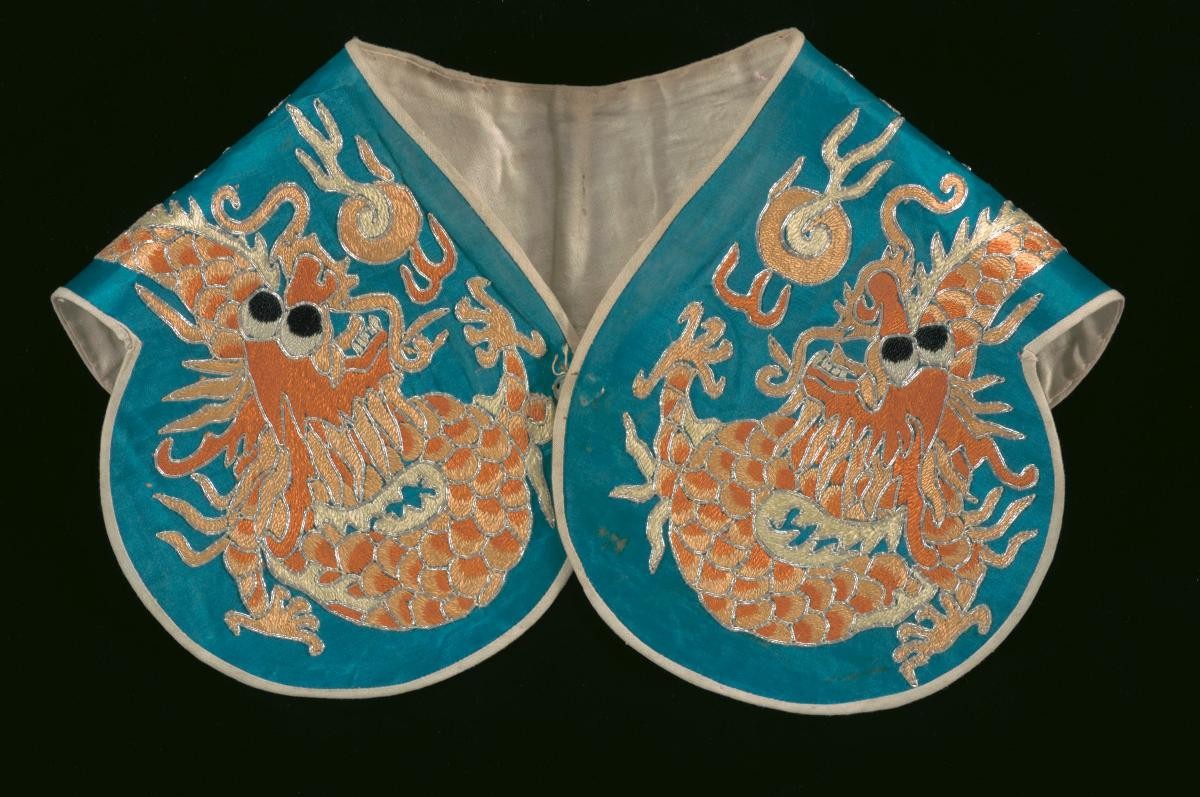 A blue shoulder piece with orange embroidered dragon motifs worn in a Chinese opera