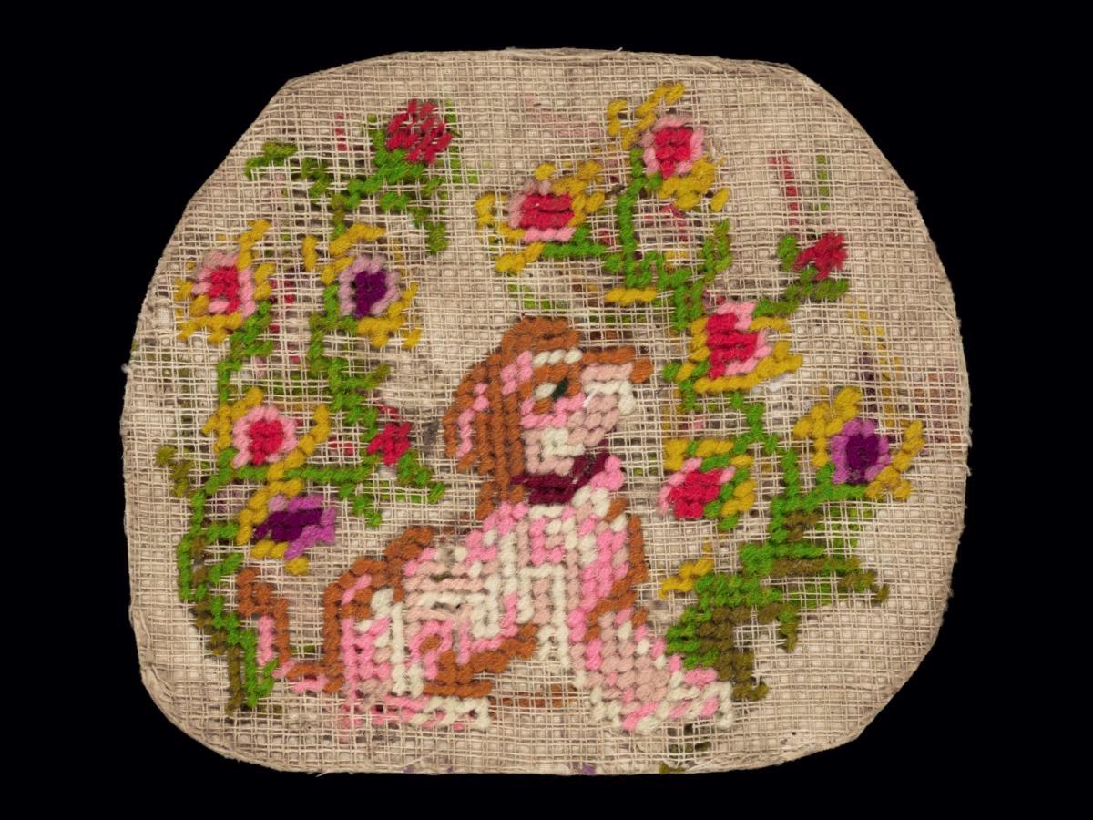 Needlework sampler with motif of dog surrounded by flowers