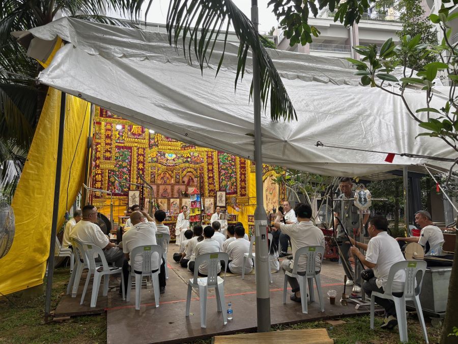 Guests in attendance at a Taoist funeral under tentage at a HDB void deck.