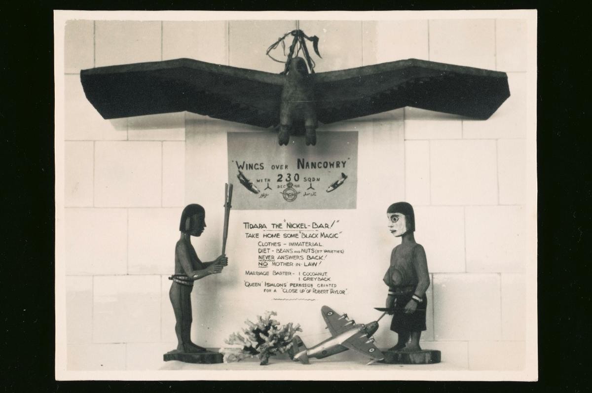 A billboard advertising a play entitled ‘Wings over Nancowry’ performed by Number 230 Squadron