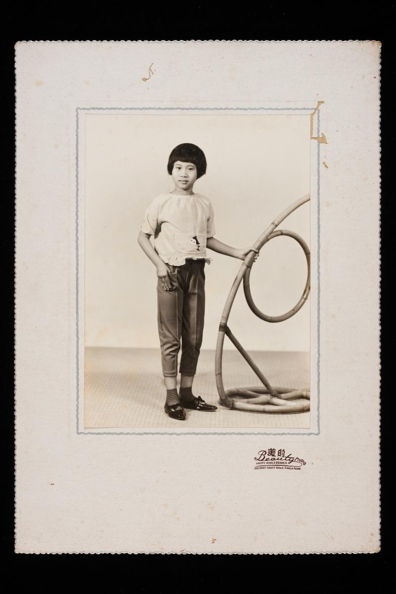 Studio portrait of a Chinese girl holding on to a bamboo support