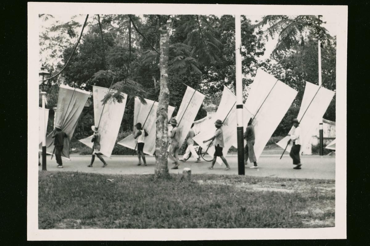 Chinese men carrying banners in a street procession