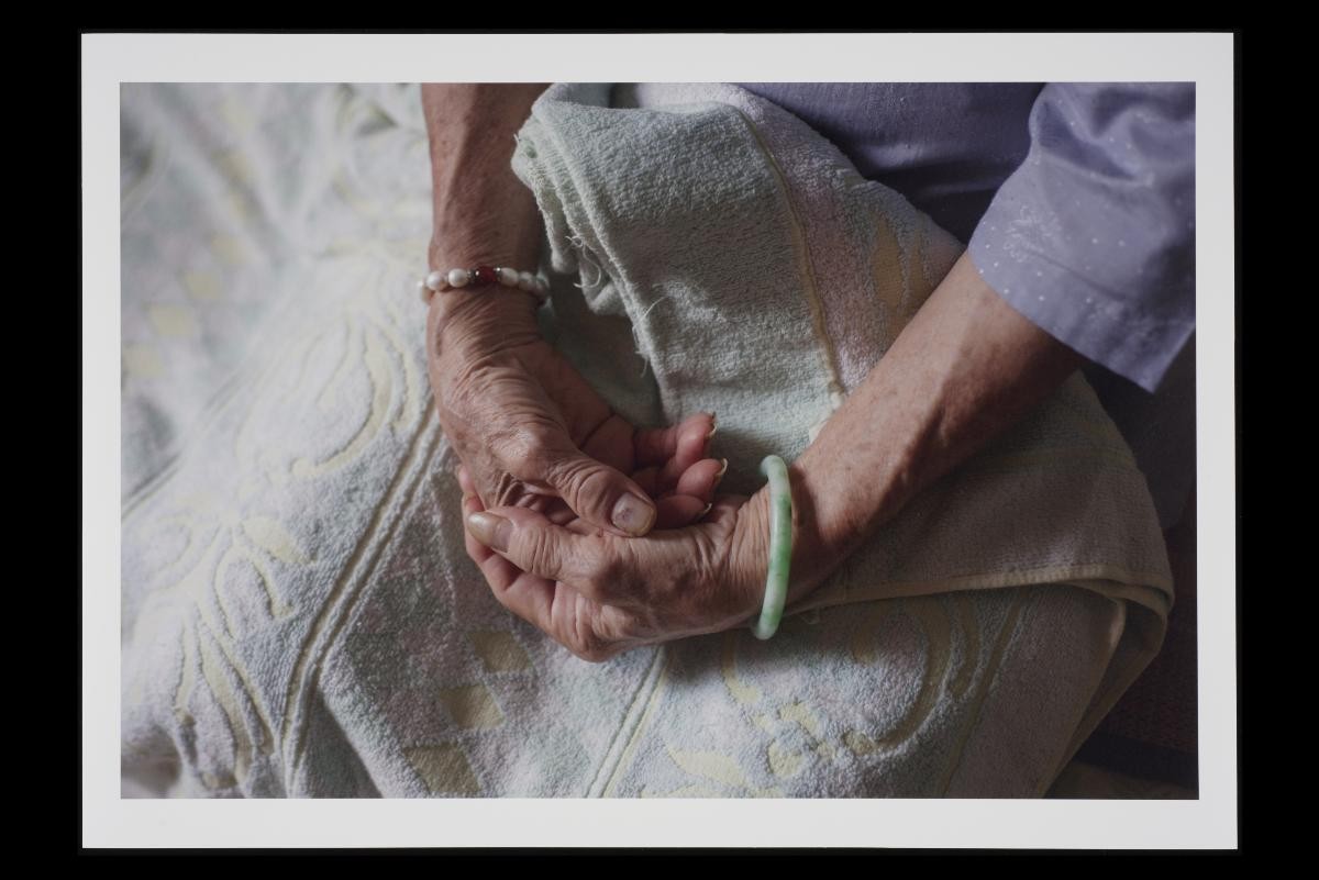 Khau Jie sits on the bed, with her hands clasped