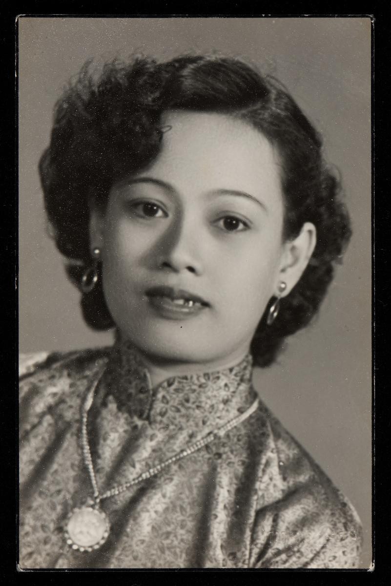 Studio portrait of a Chinese woman wearing a Cheongsam and pendant necklace