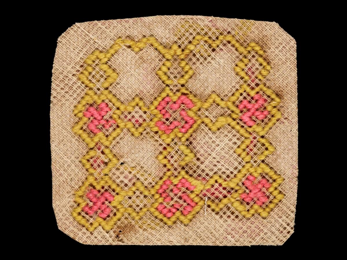 Needlework sampler with pink and yellow patterns