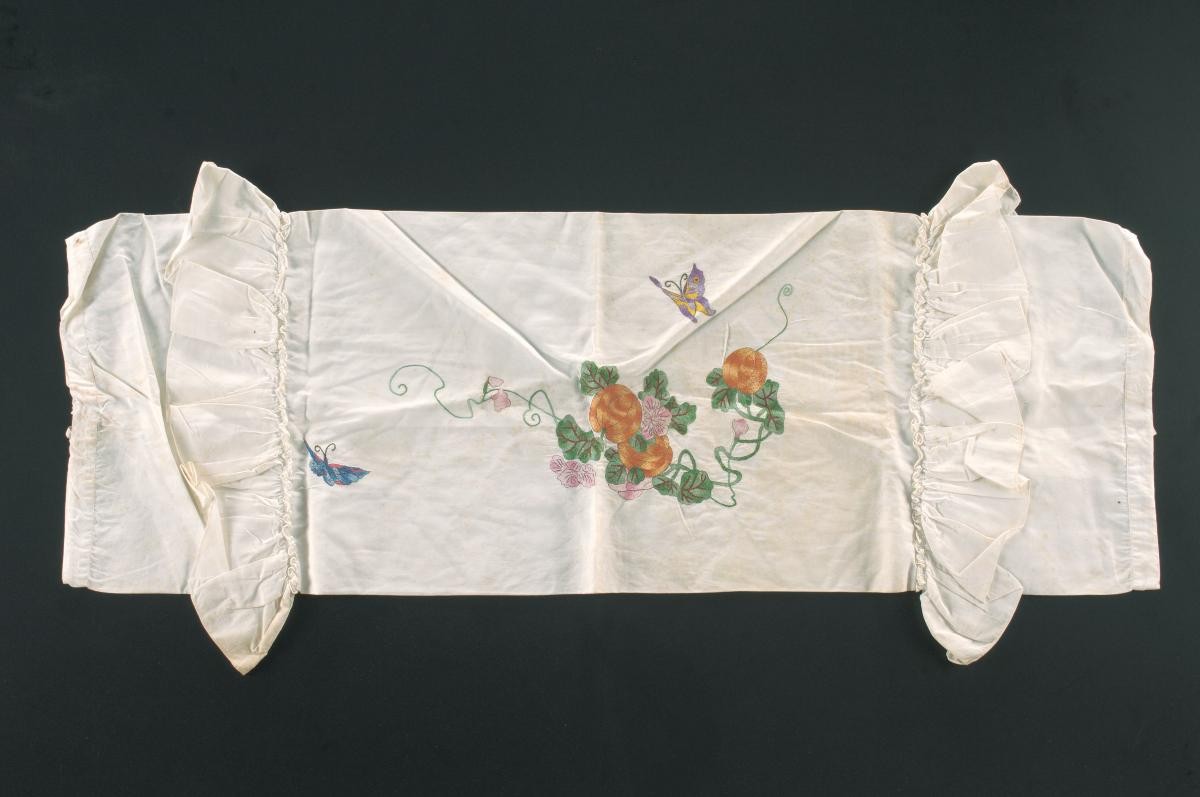 White bolster pillowcase with an embroidered butterfly and floral motif