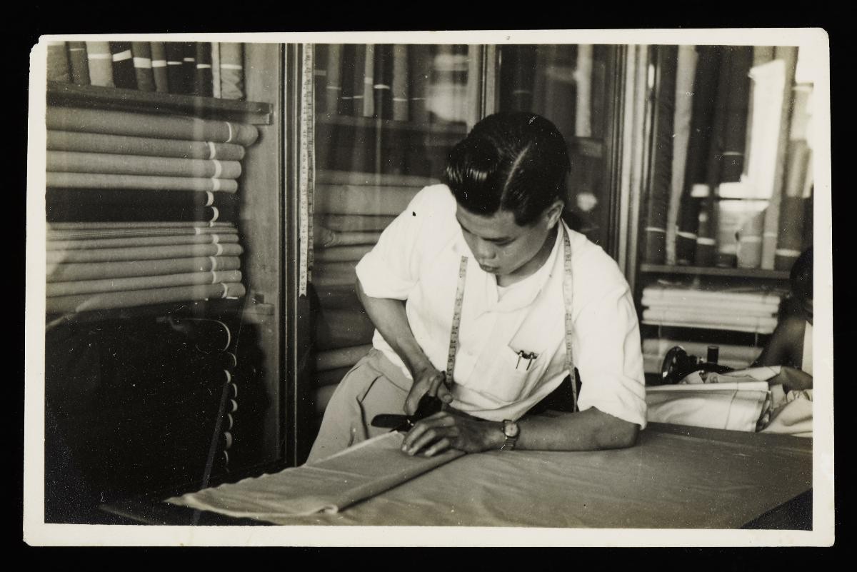 Black and white photograph of Mr Choo Foo Wah cutting fabric in his Singapore Tailor shop at 241 Jalan Besar