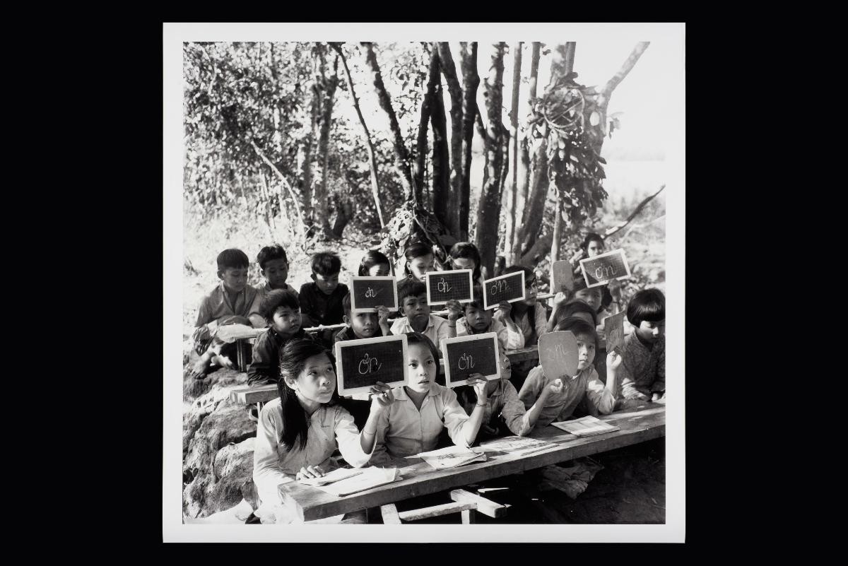 Guerilla students from Kinh Hang Hamlet, Khanh Hung Commune, Tran Thoi District, Ca Mau, seated on makeshift wooden boards which are later removed once class is over, leaving no traces behind.