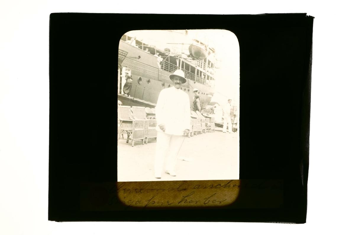 A glass lantern slide depicting a European man posing at a dock