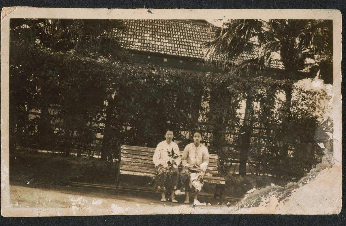 Two Nyonyas sitting on a wooden bench