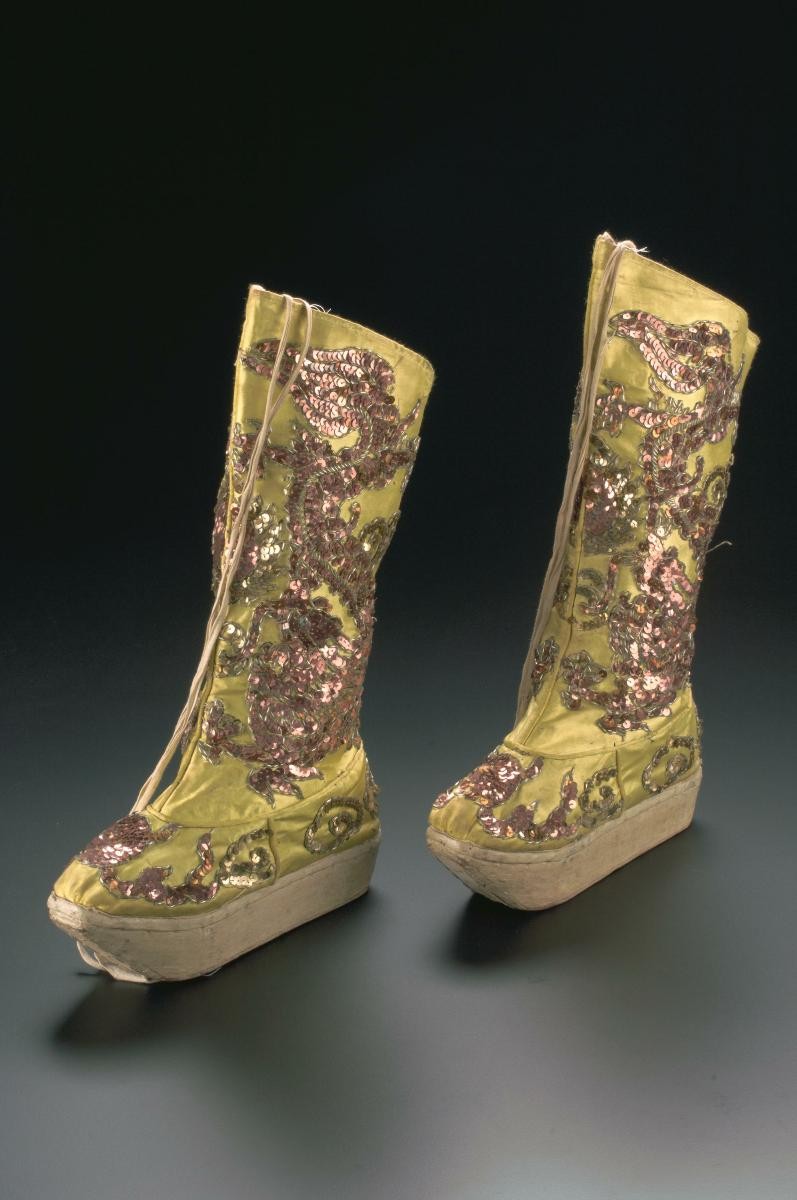 A pair of yellow platform boots with sequined dragon motifs worn in a Chinese opera performance