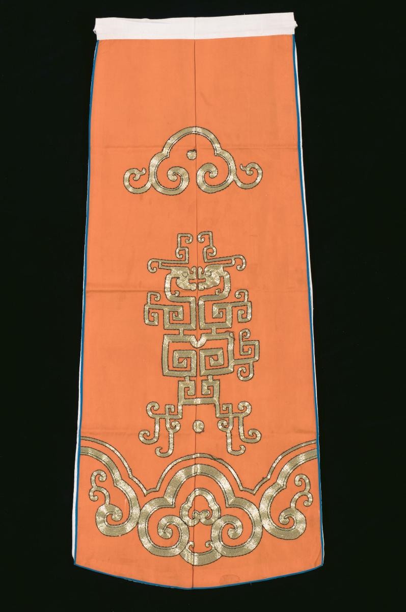 An orange waist piece with gold embroidery worn by an emperor in a Chinese opera