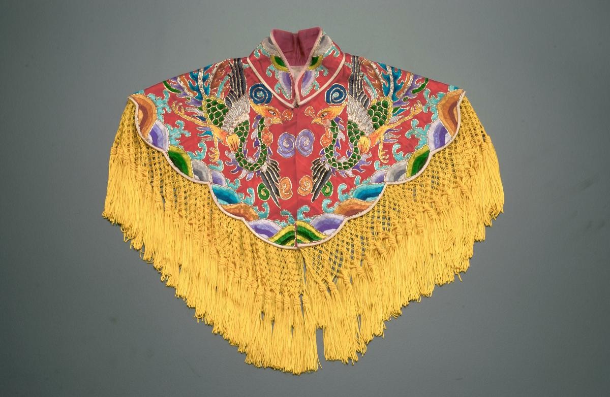 A red shoulder piece with phoenix motifs and yellow tassels