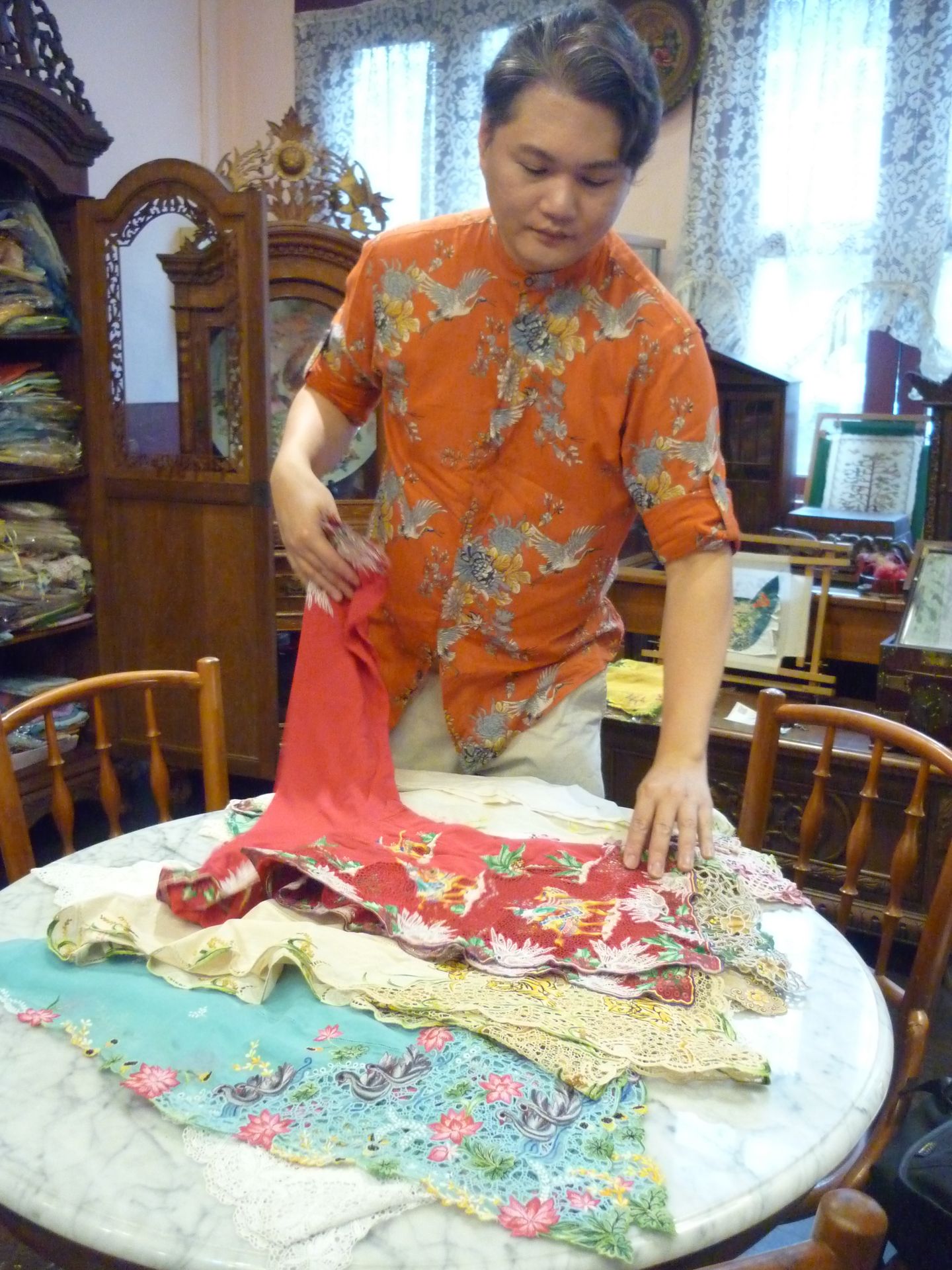 Mr Raymond Wong Sin Kong showing a selection of embroidered kebayas. A third-generation Peranakan, he is one of two such kebaya makers in Singapore.