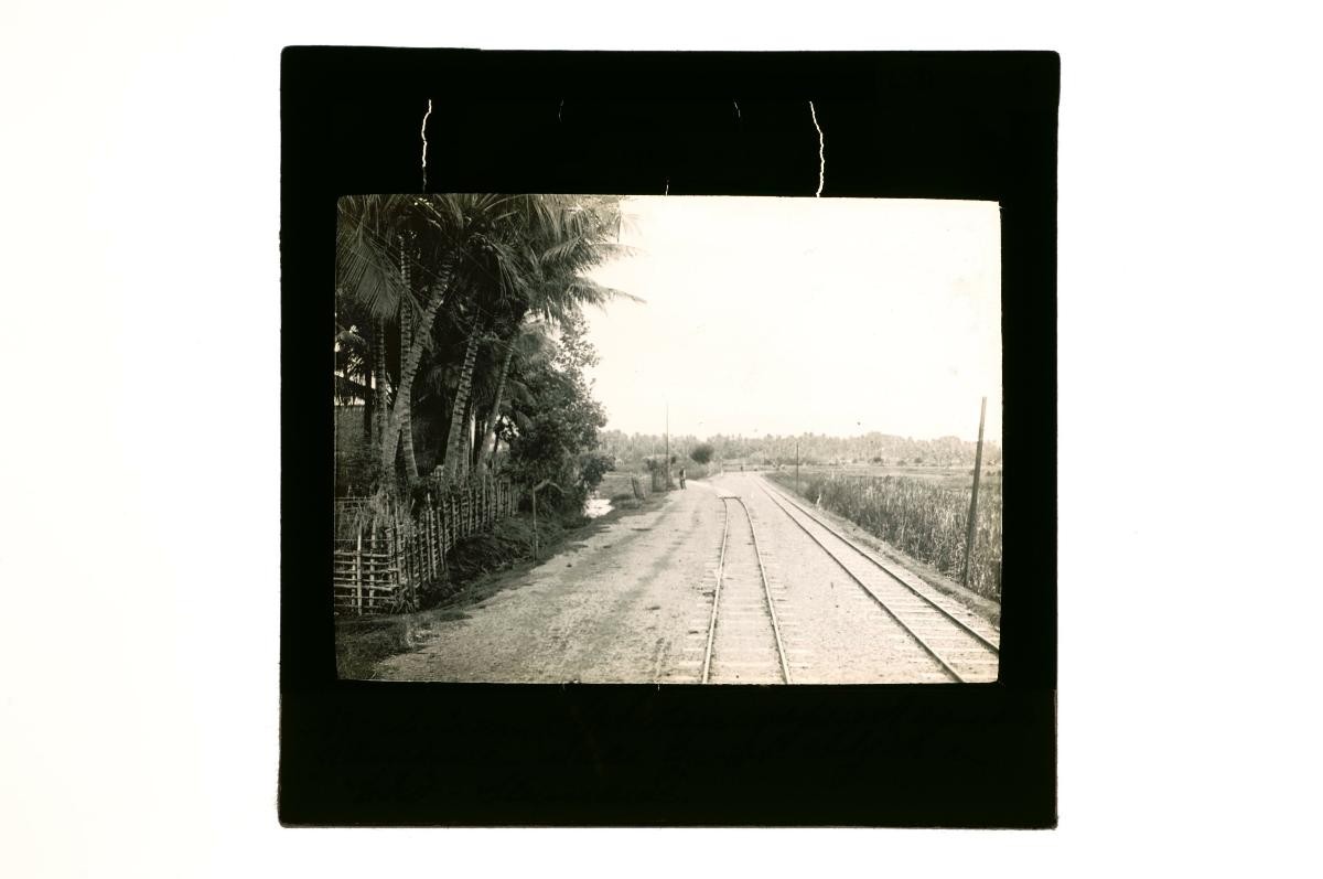 A glass lantern slide depicting railway tracks running through a rural area